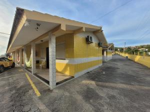 un edificio amarillo con un estacionamiento al lado en Pousada Genoveva - Apto com dois dormitórios, en Laguna