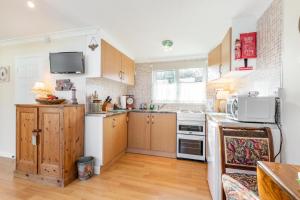 a kitchen with wooden cabinets and a microwave at The Bee's Knees in Mundesley