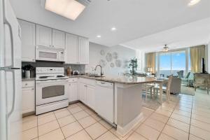 cocina con electrodomésticos blancos y comedor con mesa en Lighthouse unit 1012 - Luxury Beachfront Condo, en Gulf Shores