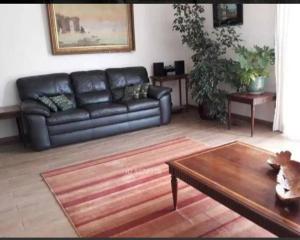 Sala de estar con sofá de cuero negro y mesa de centro en SantoDomingoLitoral122, en Santo Domingo