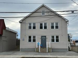 una casa blanca con una puerta azul en una calle en JD Apartment and House en Seaside Heights