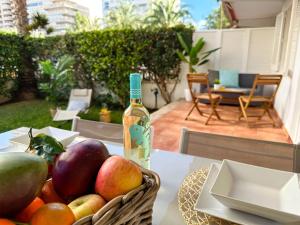 a basket of fruit and a bottle of wine on a table at Jardín Playa San Juan in Alicante