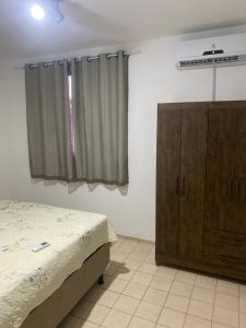 a bedroom with a bed and a wooden cabinet at Martin Quintanilha 1B in Goiânia