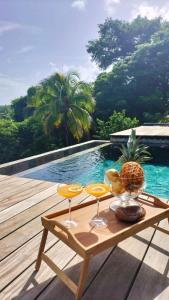 einen Tisch mit Weingläsern und eine Ananas auf dem Deck in der Unterkunft Le CAILLOU in La Trinité