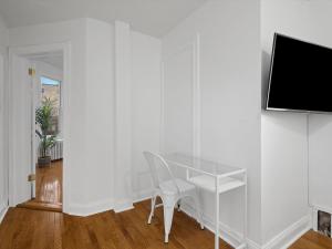 escritorio blanco con silla y TV en la pared en Bloomfield/Shadyside @F Quiet and Stylish Private Bedroom with Shared Bathroom, en Pittsburgh