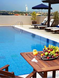 a tray of fruit on a table next to a swimming pool at Citymax Hotel Al Barsha at the Mall in Dubai