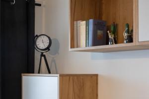 zegar na statywie obok półki na książki w obiekcie Apartament przy PILECKIEGO 34 w Białej Podlaskiej