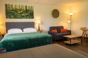 a bedroom with a large green bed and a couch at Wayside Motel Manitoulin in Manitowaning