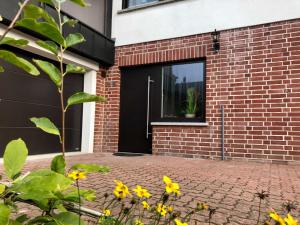 una casa de ladrillo con una puerta negra y flores amarillas en Anikas Ferienwohnung 1, en Wustrow