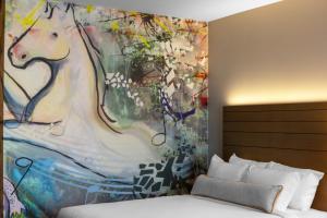 un dormitorio con una pintura en la pared junto a una cama en Hotel Indigo Gainesville-Celebration Pointe, an IHG Hotel, en Gainesville