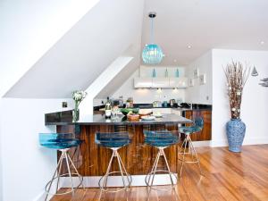 a kitchen with a counter and blue stools at 9 The Whitehouse in Mawgan Porth