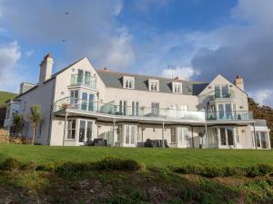 a large white house on a grassy field at 9 The Whitehouse in Mawgan Porth