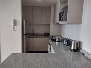une cuisine avec des placards blancs et un comptoir gris dans l'établissement Departamentos Terramar, à Puerto Montt