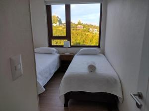 a room with two beds and a large window at Departamentos Terramar in Puerto Montt