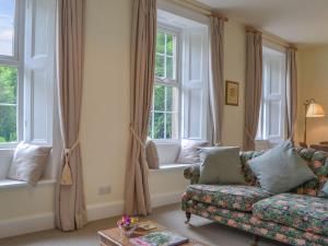 a living room with a couch and two windows at Monkwood Cottage in Hale