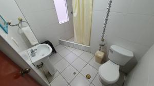 a white bathroom with a toilet and a sink at Andes Colca Hostal in Chivay