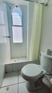 a white bathroom with a toilet and a window at Andes Colca Hostal in Chivay