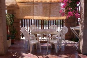 patio con tavolo, sedie e recinzione di Su Suergiu a San Giovanni Suèrgiu