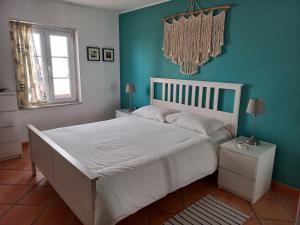 um quarto com uma cama branca e uma parede azul em Aldeia Formosa - Cabanas de Tavira em Cabanas de Tavira