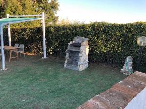 a stone fireplace in a yard next to a hedge at Villetta a schiera nei pressi del mare in Livorno