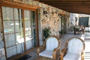 a patio with two chairs and a table and windows at Kaya Koy Deluxe Villas Fethiye in Fethiye