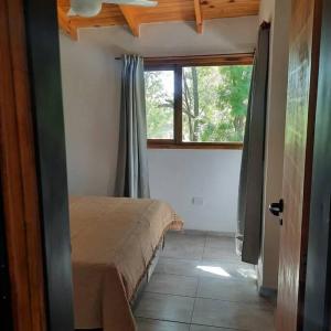 1 dormitorio con 1 cama en una habitación con ventana en Las Casitas del Pozo en Villa General Belgrano