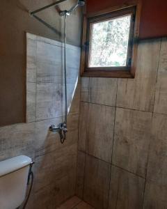 baño con ducha y puerta de cristal en Las Casitas del Pozo en Villa General Belgrano