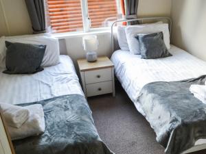 two twin beds in a room with a window at Griffon Lodge - Uk3469 in Felton