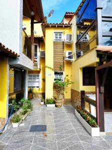 un patio de un edificio amarillo con macetas en Loft Búzios, en Búzios