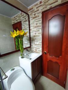 uma casa de banho com WC e um vaso de flores amarelas em Apartamento en el Centro de Paipa em Paipa
