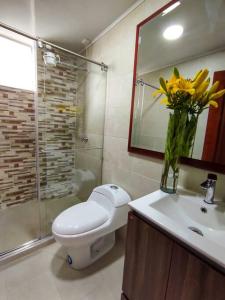 baño con aseo y jarrón de flores amarillas en Apartamento en el Centro de Paipa, en Paipa