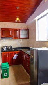 cocina con armarios de madera y nevera de acero inoxidable en Apartamento en el Centro de Paipa, en Paipa
