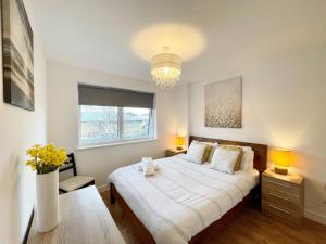 a bedroom with a large bed and a chandelier at Hamptons Point in Enfield