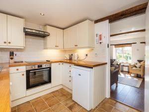 a kitchen with white cabinets and a counter top at Primrose Cottage in Aylmerton