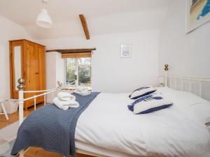 a bedroom with a white bed with towels on it at Primrose Cottage in Aylmerton