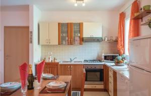 a kitchen with wooden cabinets and a table with red chairs at Stunning Home In Nedescina With Outdoor Swimming Pool in Nedeščina