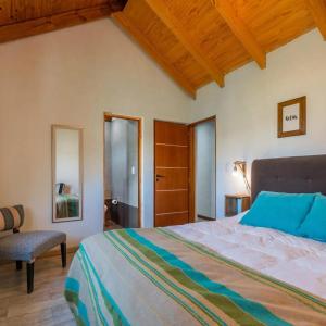 1 dormitorio con 1 cama grande y 1 silla en PEWMA Casa de Montaña en Caviahue