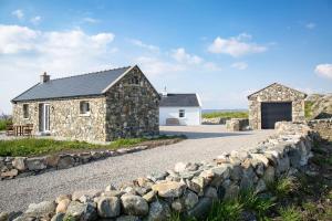 a stone house with a garage and a stone wall at Paddy Carrolls Cottage in Ballyconneely