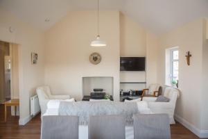 a living room with white furniture and a fireplace at Paddy Carrolls Cottage in Ballyconneely