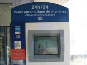 una máquina atm en un edificio con una señal en ibis Budget Gennevilliers Asnieres, en Gennevilliers