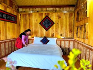 een vrouw die naast een bed in een kamer staat bij Hoa Phong homestay Moc Chau in Mộc Châu