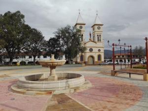 une fontaine en face d'un bâtiment avec une église dans l'établissement Posada Turística Estancia Real, à Sutamarchán