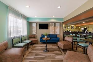 a waiting room with a blue couch and chairs at SureStay Plus Hotel by Best Western Elizabeth City in Elizabeth City