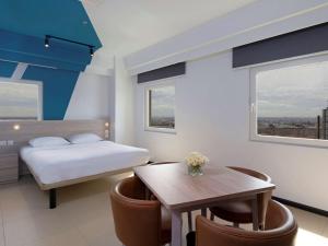 ibis budget Phnom Penh Riverside في بنوم بنه: غرفة فندقية بسرير وطاولة وكراسي