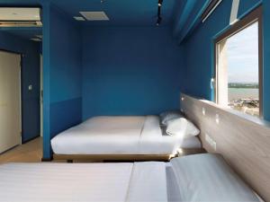 um quarto azul com duas camas e uma janela em ibis budget Phnom Penh Riverside em Phnom Penh