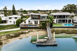 a house on the water with a boat in the water at 7 bedroom home on Mooloolaba canal in Mooloolaba