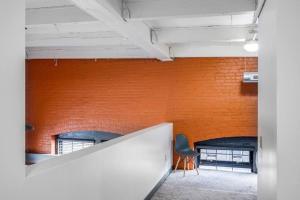 eine orangefarbene Backsteinwand in einem Zimmer mit Stuhl in der Unterkunft Centric Modern Loft w/ King Beds & Smart GameTable in Rochester