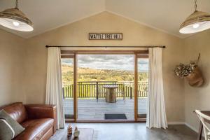 a living room with a couch and a large sliding glass door at WATTLE TREE HILL in Gundagai