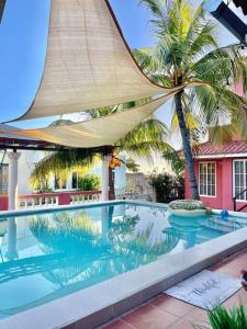 a swimming pool with palm trees and a building at Nuestro Castillo, Playa San Blas, La Libertad, El Salvador in La Libertad