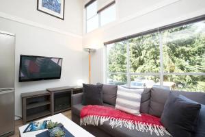 a living room with a gray couch and a large window at Gondola Haus - Free parking in Whistler
